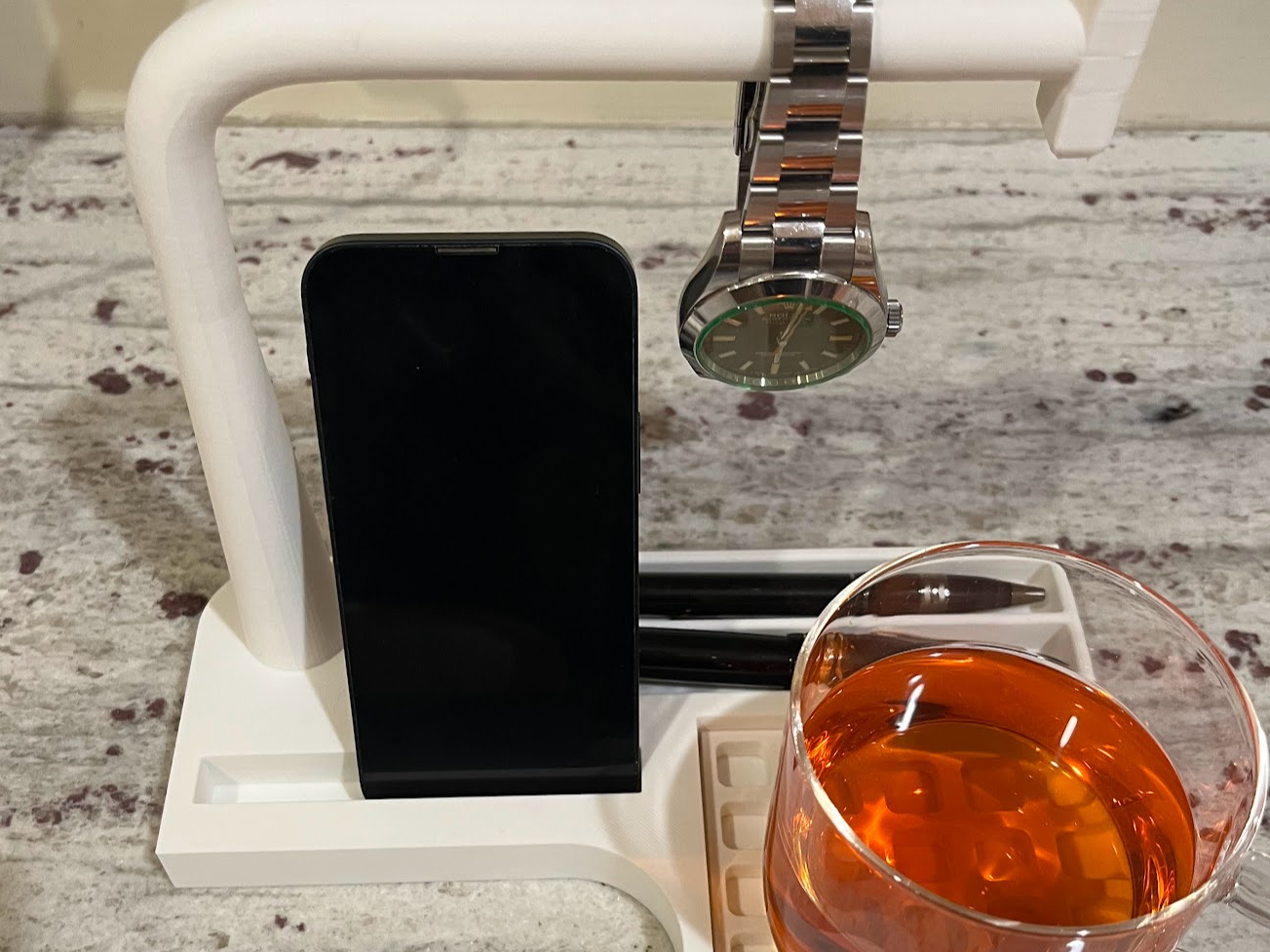 Desk caddy. Watch bar; slots: cup, phone, and pens