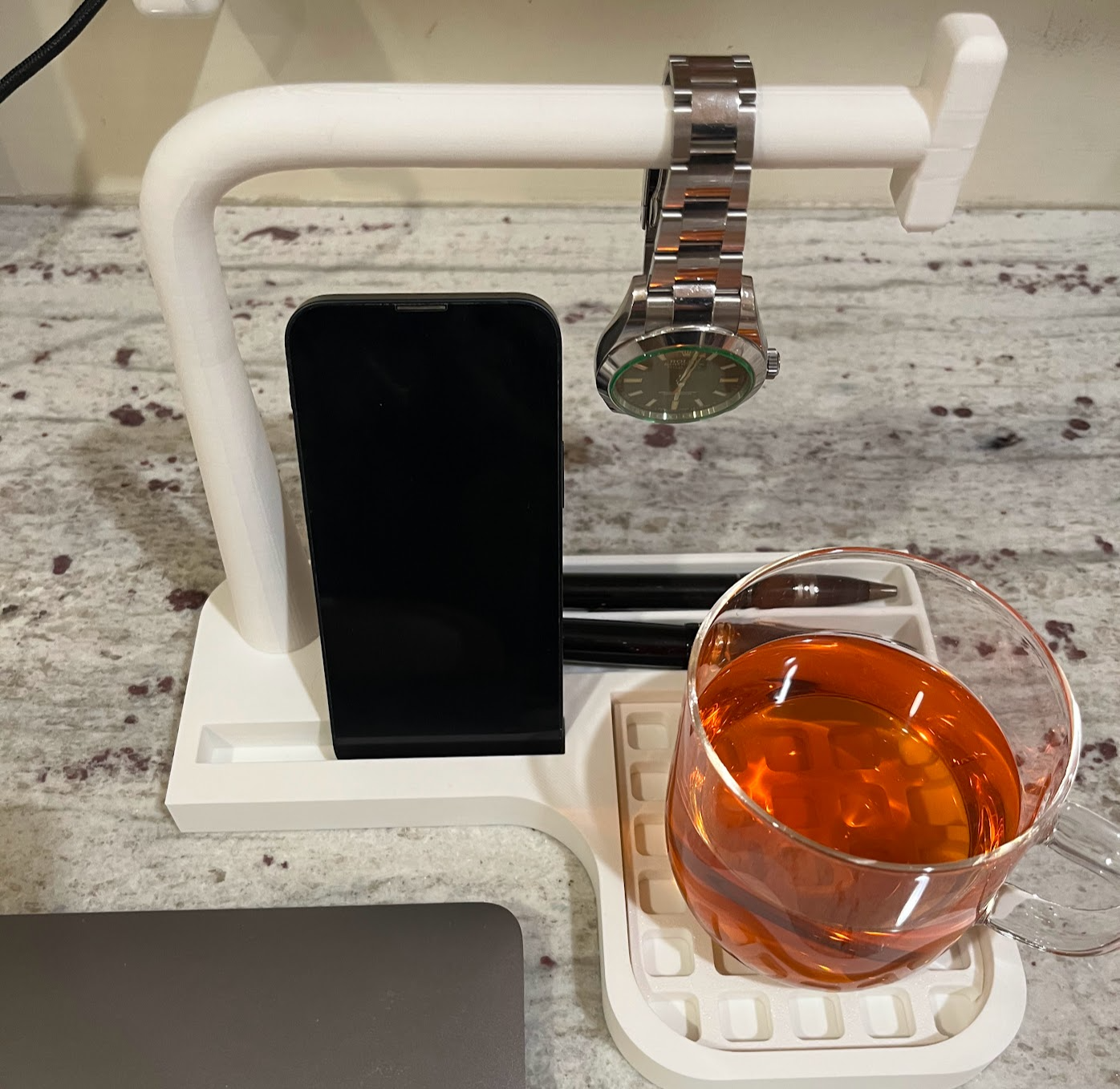 Desk caddy. Watch bar; slots: cup, phone, and pens